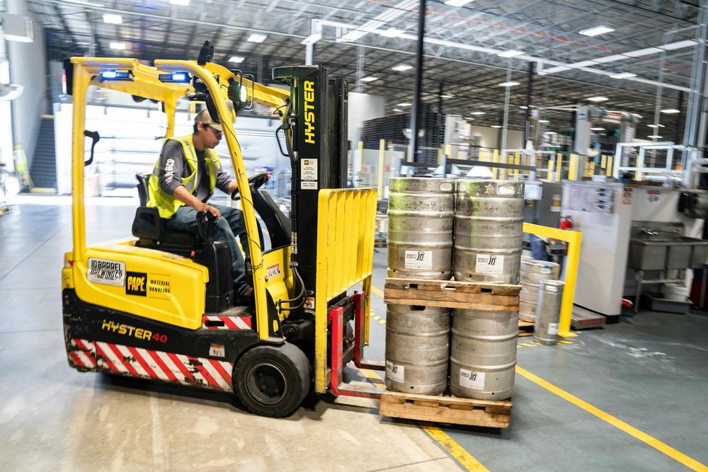 Depoda palet üzerinde yük taşıyan forklift ve operatörü