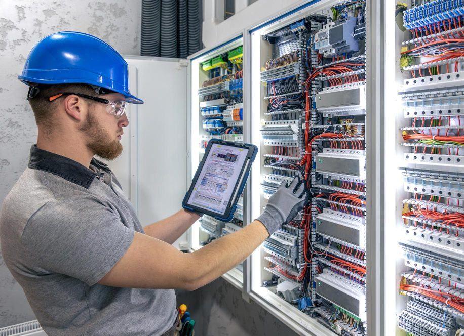 Elektrik panosunu tablet üzerinden kontrol eden teknisyen